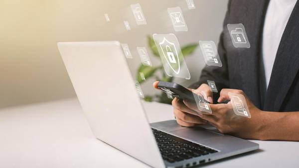 A businessman works on his laptop at home with a virtual display showing a symbol to signify cyber security privacy and online data protection