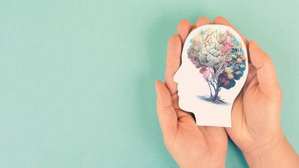 Hands holding paper head, human brain with flowers, self care and mental health concept, positive thinking, creative mind