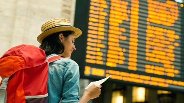 Young woman checking her flight on time board