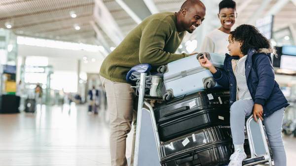 Tourist family with luggage trolley at airport 