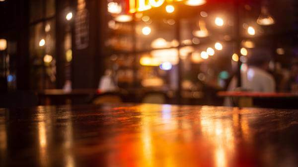 Empty real wood table top with light reflection on scene at restaurant, pub or bar at night