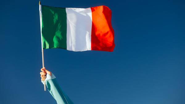 Hand Waiving an Italian Flag on a Blue Sky