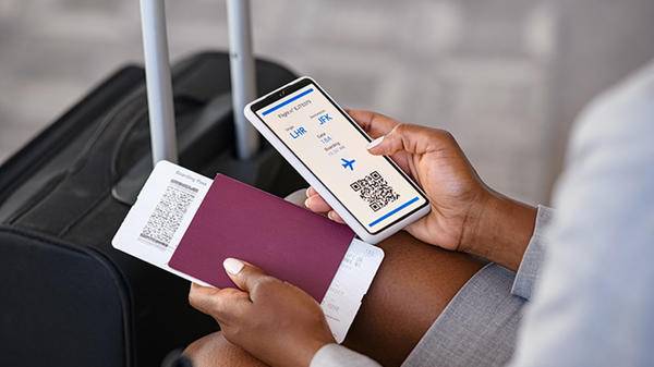 Business person using phone and holding passport airport