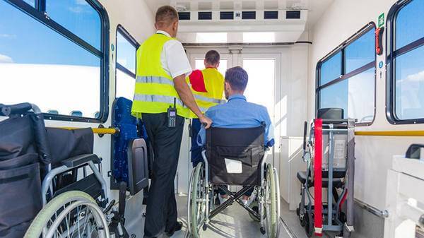 Disabled traveller with airport staff getting support