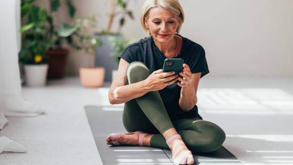 Senior Woman Checking Smartphone After Yoga Session at Home