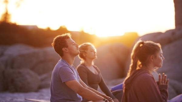 Shot of a group of people practising yoga on the beach