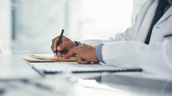 Doctor hands writing on paper or document at a desk in the hospital