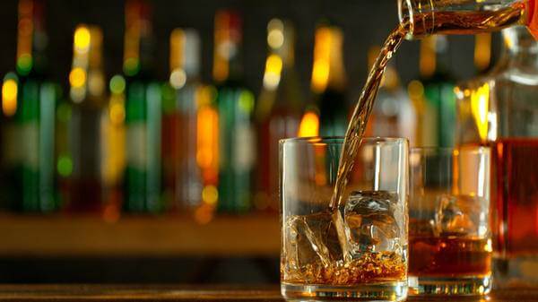 Close-up of pouring whiskey or rum on the bar