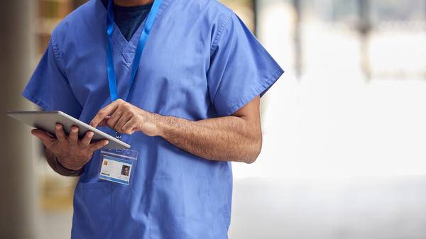 Close Up Of Male Medical Worker In Scrubs With Digital Tablet In Hospital 