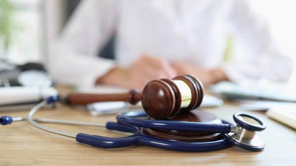Closeup of judge gavel of stethoscope doctor in background writing notes