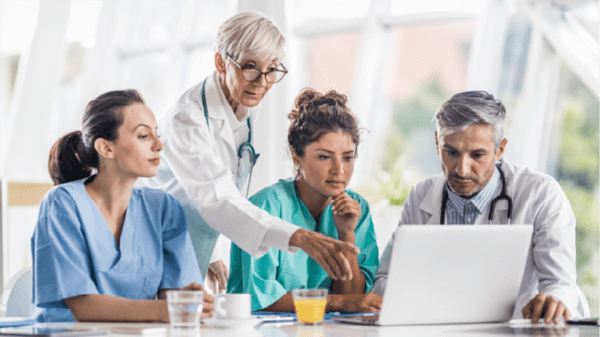 Group of healthcare workers having a discussion and pointing at a laptop