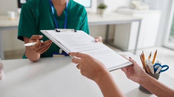 Patient giving filled questionnaire to medical nurse