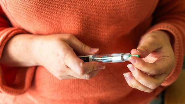 Close up of a woman's hands holding a weight loss injection syringe