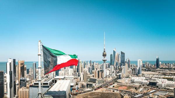Kuwait flag waving in the wind over the Kuwait City cityscape