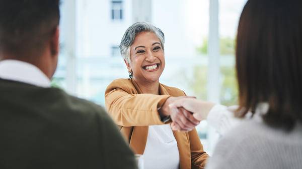 Handshake, job interview or business people with a happy mature woman for partnership in office