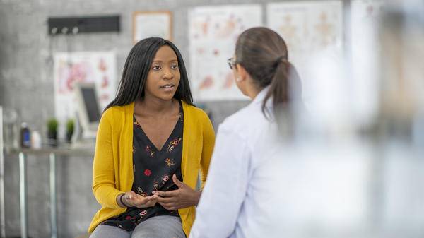 woman is sitting and describing her symptoms to the doctor