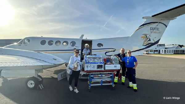 Nurses with a patient in front of a plane