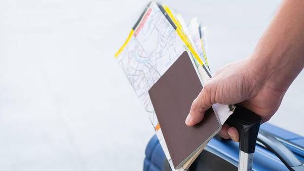 Traveler man holding passports, map for travel with luggage for the trip, copy space for text