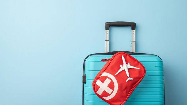 A symmetrical image of a blue suitcase is complemented by a red travel emergency kit