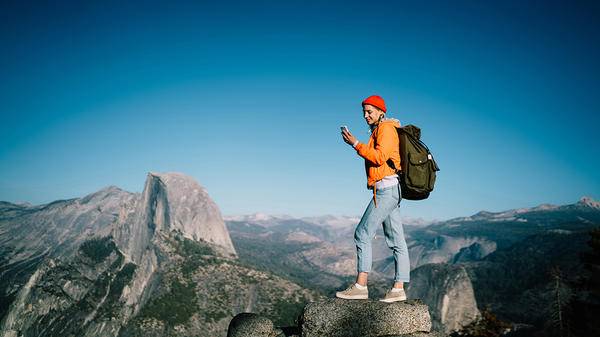 Woman hiking on a mountain and using her phone 