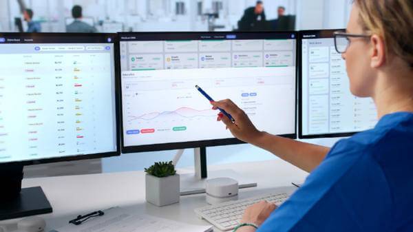 Woman looking at a computer monitor with a graph displayed.