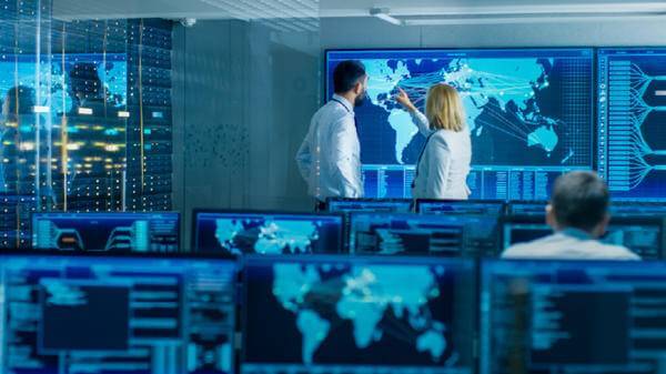 A man and a woman looking at a map of the world in a control room 
